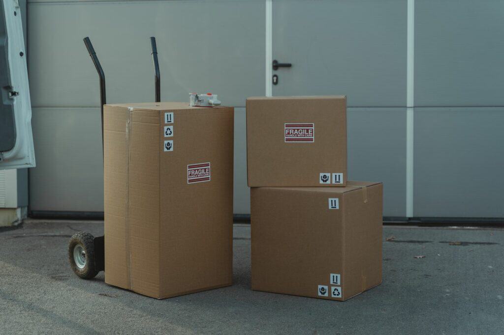 Brązowe kartony klapowe e-commerce z piktogramami recyklingu i „FRAGILE" — opakowania a rozporządzenie PPWR