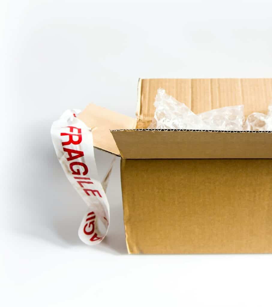 Otwarty karton klapowy z folią bąbelkową i taśmą „FRAGILE" — wybór opakowania do wysyłki w e-commerce