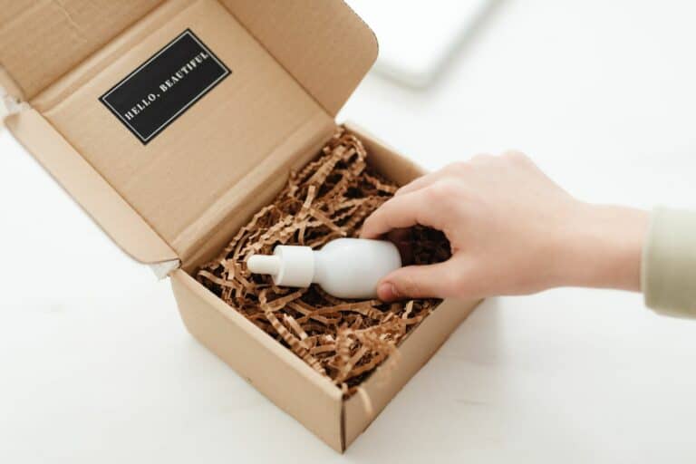 Otwarte kartonowe pudełko z wypełnieniem papierowym i kosmetykiem — unboxing boxa subskrypcyjnego