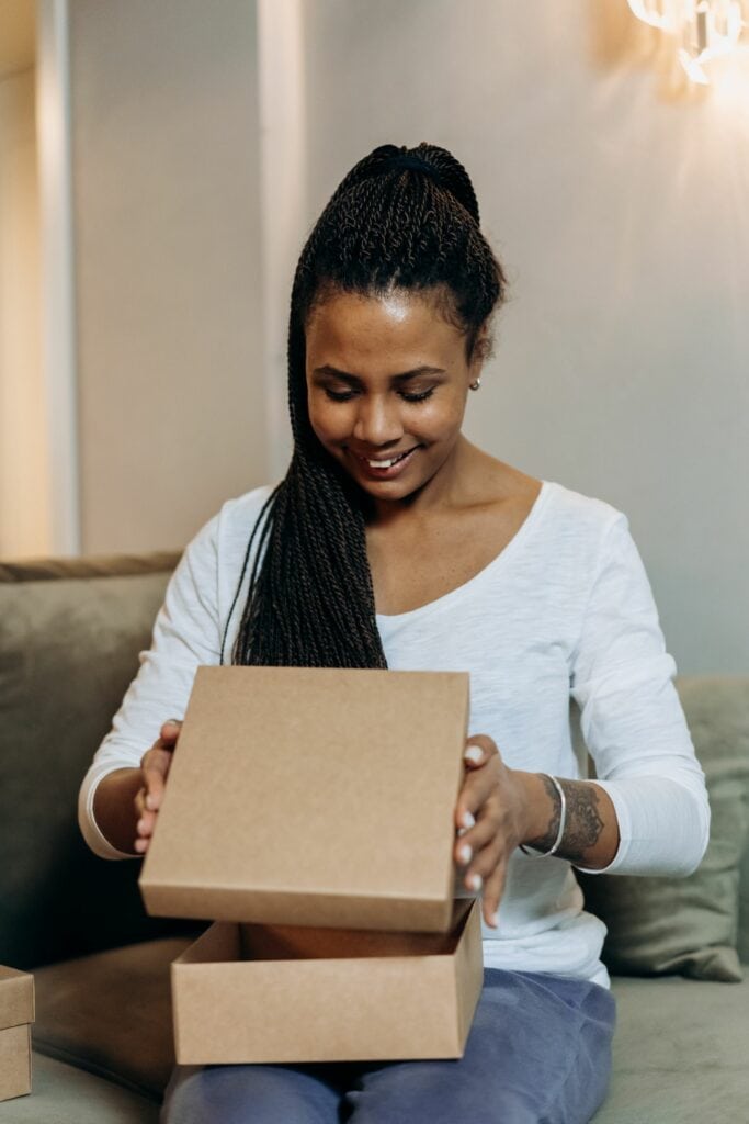 Uśmiechnięta klientka otwiera kartonowe pudełko — unboxing zamówienia z TikTok Shop