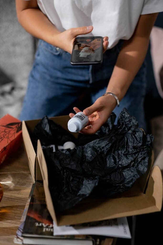Kobieta wyjmuje produkt z kartonu i nagrywa unboxing telefonem na TikToka