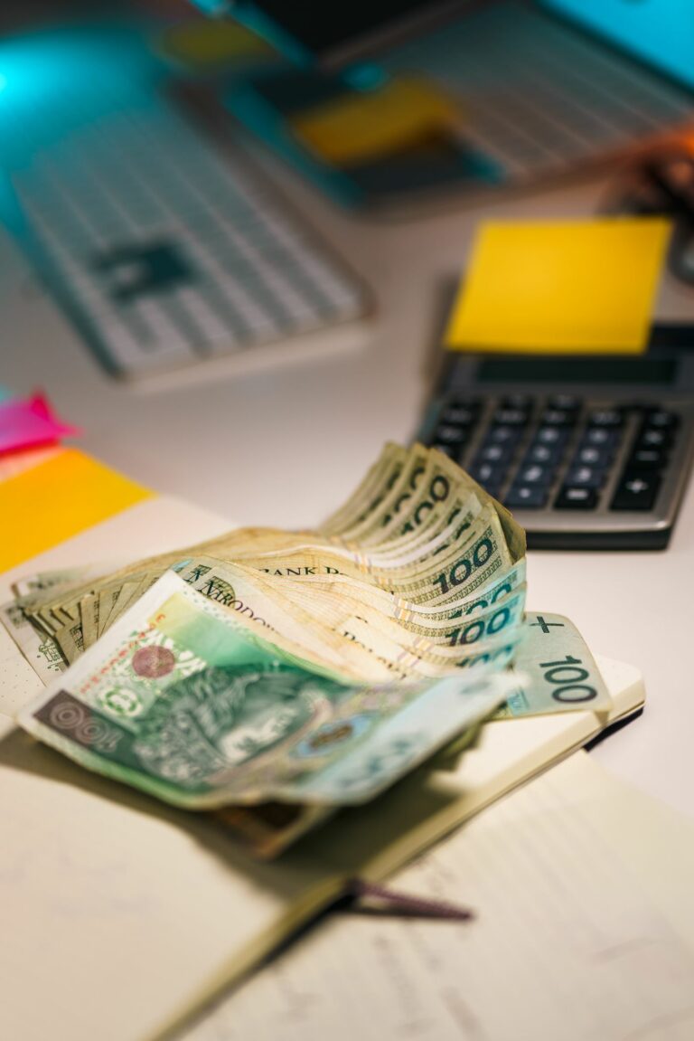 Polskie banknoty i kalkulator na biurku — liczenie kosztów kartonów