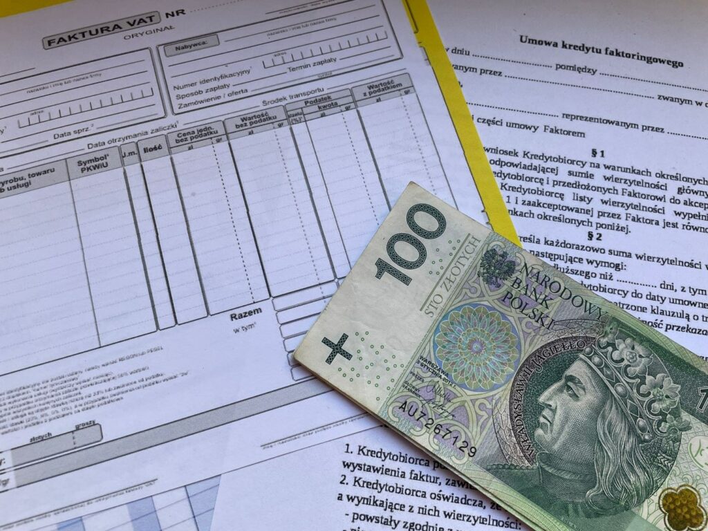 Papierowy formularz faktury VAT z banknotem stuzłotowym i umową